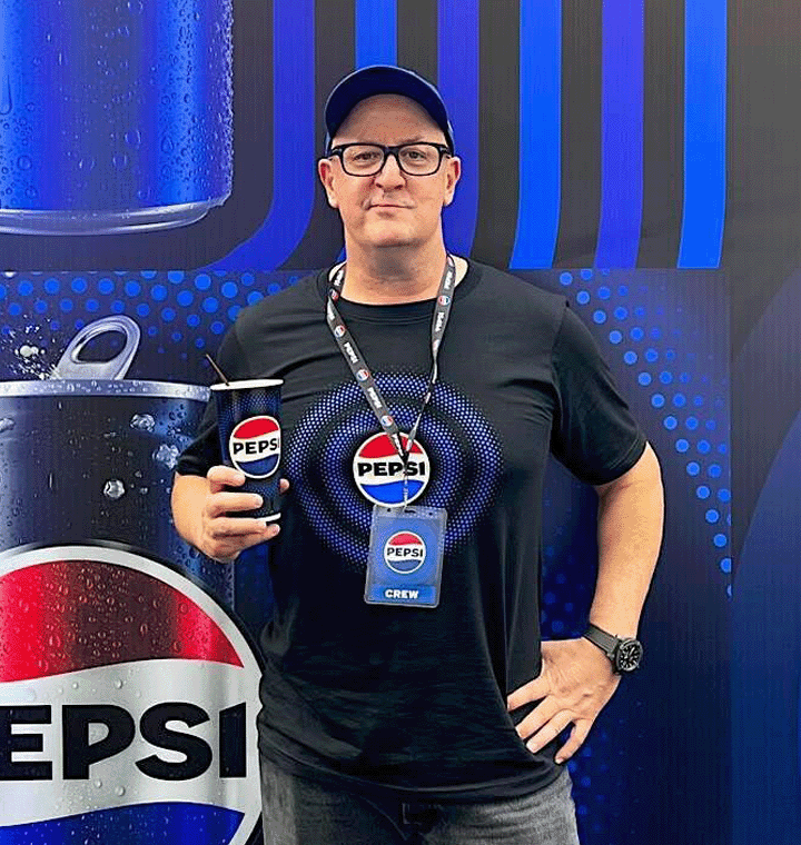 Employee wearing Pepsi brand shirt holding a Pepsi cup