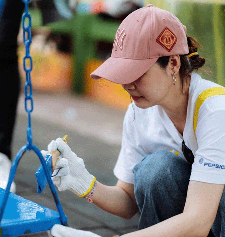 Female employee painting a swing at a volunteer event